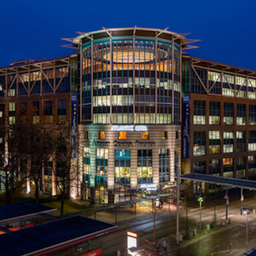 Außenansicht des ATLANTIC Hotel Airport Bremen bei Nacht, beleuchtetes modernes Gebäude mit Glasfassade.