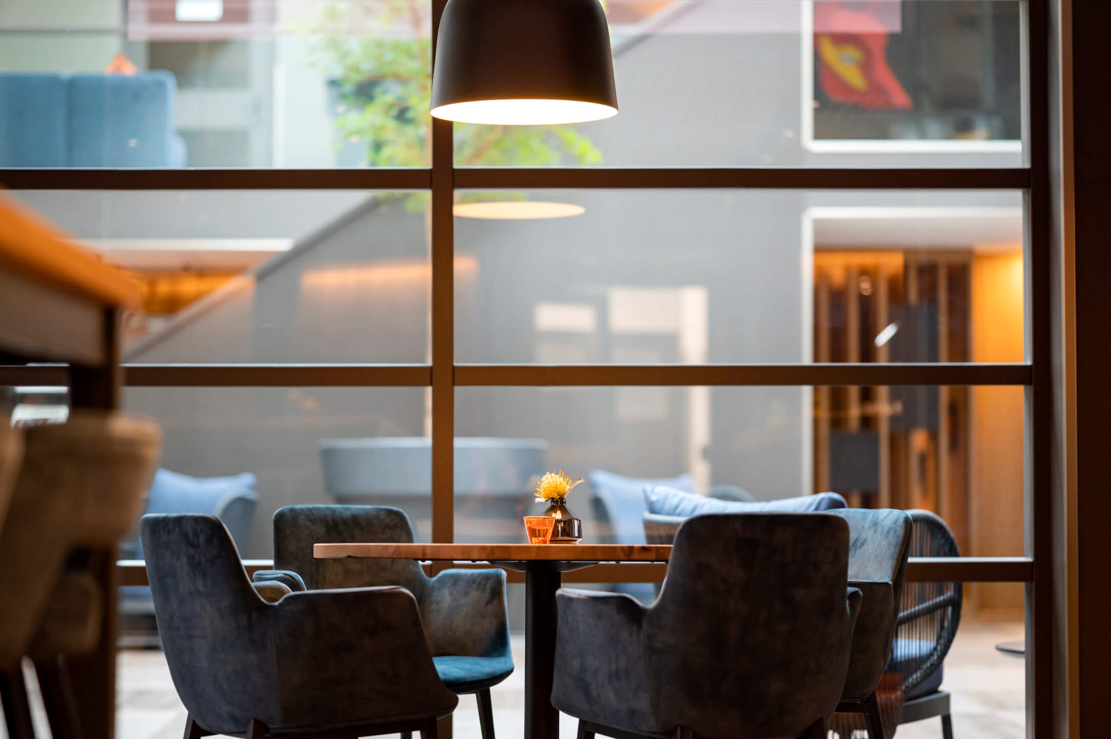 Gemütlich Sitzen im Restaurant VICTORIAN im ATLANTIC Hotel Landgut Horn Gemütliche Sitzecke im ATLANTIC Hotel Landgut Horn mit Tisch, blauer Polsterung und stilvoller Beleuchtung.