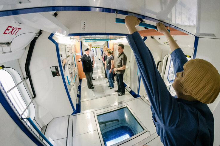 Columbus Modul | Raumfahrt-Führung Bremen Personengruppe in einem Raumstationsnachbau, umgeben von technischen Geräten und einer Schaufensterpuppe im Vordergrund.