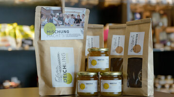 ATLANTIC Hotel Sail City Regio Shop Produkte Lokale Produkte im ATLANTIC Hotel: Weserhonig, Deichling-Mischung und Beanbooster-Kaffee auf einem Tisch.