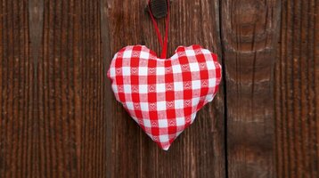 Stoff Herz an einer Holzwand im ATLANTIC Grand Hotel in Bremen Rot-weiß kariertes Stoffherz hängt an rustikaler Holzwand im ATLANTIC Grand Hotel Bremen.