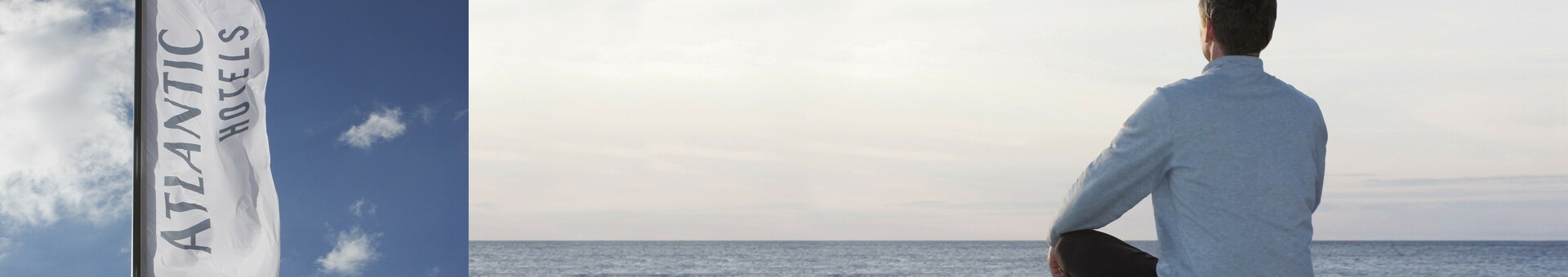 Fahne mit Logo der ATLANTIC Hotels und einem Mann, der am Meer sitzt Eine Flagge mit „Atlantic Hotels“ weht im Wind; daneben sitzt eine Person am Meer und blickt auf den Horizont.