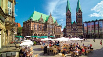 Bremer Marktplatz im Sommer Belebter Platz mit historischem Gebäude, Dom und Café-Terrasse unter Sonnenschirmen bei blauem Himmel.