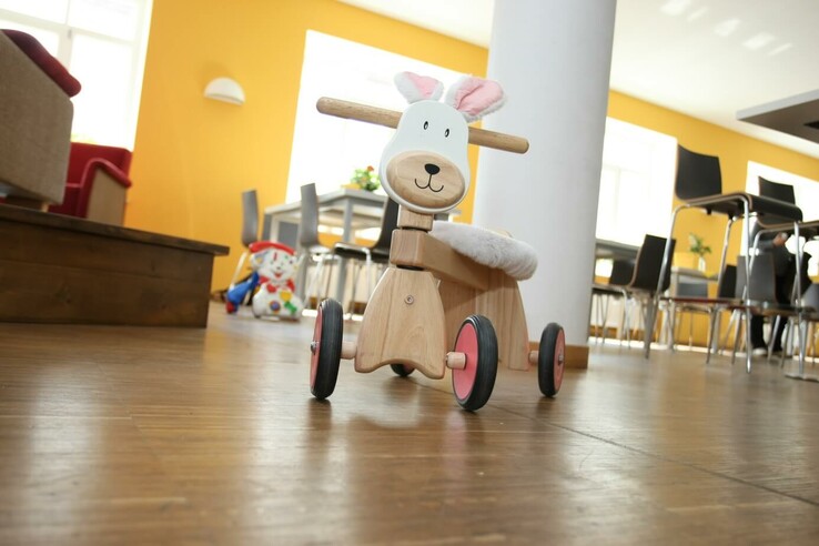 SOS Kinderdorf Holzspielzeug in Tierform auf Holzboden in hellem Raum mit gelber Wand und modernen Möbeln. © SOS Kinderdorf