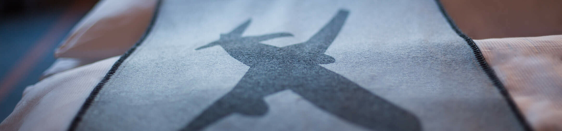 Die Tagesdecke im Business Zimmer des ATLANTIC Hotel Airport Bremen Bettdecke im ATLANTIC Hotel Airport Bremen mit Flugzeugmotiv, im Hintergrund verschwommene Fensteransicht.
