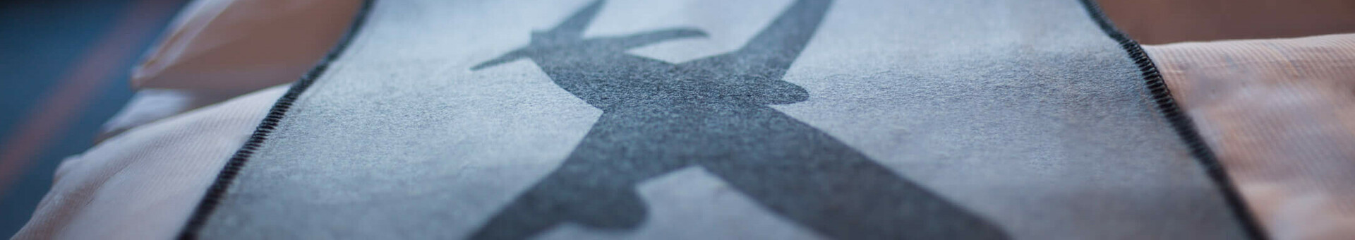 Die Tagesdecke im Business Zimmer des ATLANTIC Hotel Airport Bremen Bettdecke im ATLANTIC Hotel Airport Bremen mit Flugzeugmotiv, im Hintergrund verschwommene Fensteransicht.