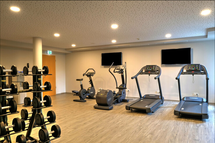 Fitnessbereich ATLANTIC Hotel Airport Bremen Heller Fitnessraum mit Laufbändern, Fahrrädern und Hanteln im ATLANTIC Hotel Airport Bremen.