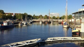 Hafen von Vegesack © Fritz Rapp Hafenansicht mit Booten im Wasser, umgeben von Gebäuden und Bäumen, bei klarem Himmel in Bremen Vegesack.