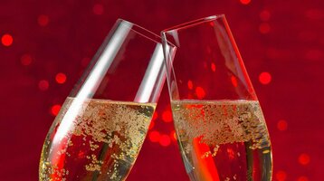 Zwei Sektgläser vor rotem Hintergrund Zwei Sektgläser stoßen vor rotem, funkelndem Hintergrund an.