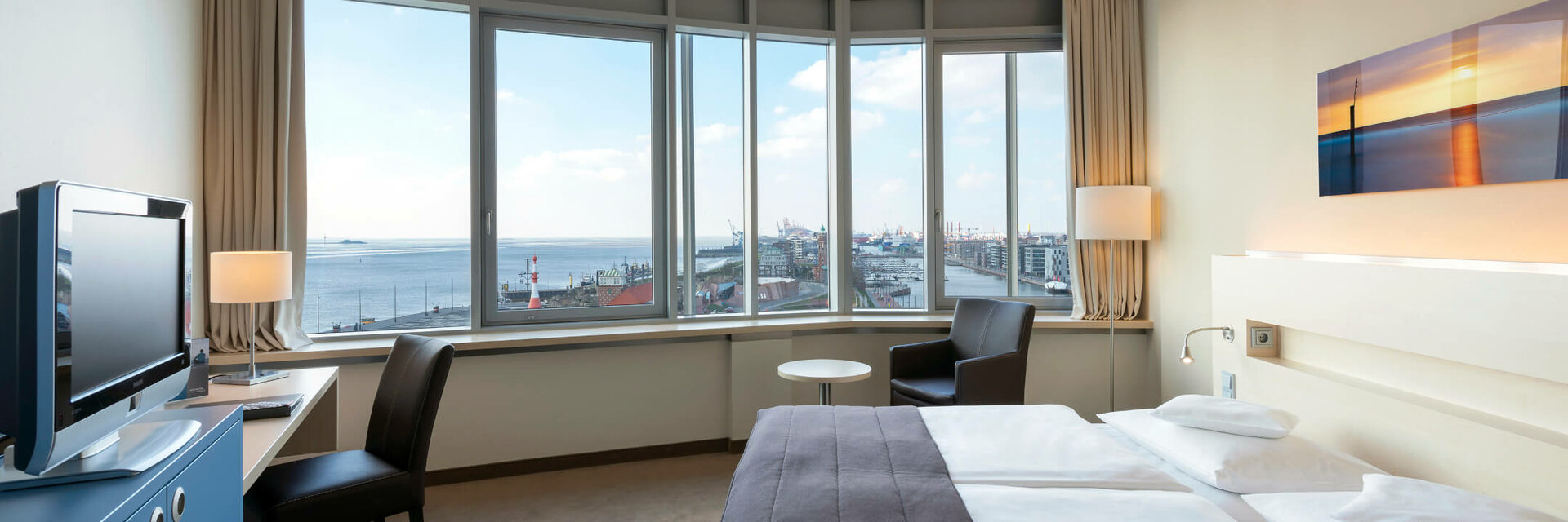 Superior Zimmer im ATLANTIC Hotel Sail City Helles Hotelzimmer mit Doppelbett, großem Fenster und Blick auf den Hafen von Bremerhaven.