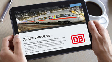 Tablet zeigt eine Hotelwebseite mit ICE-Zug und DB-Logo, daneben eine Tasse Kaffee auf einem Tisch.