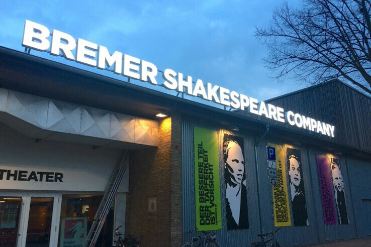 © bremer shakespeare company Theaterfassade mit "Bremer Shakespeare Company" Schriftzug und bunten Plakaten, Abendstimmung.