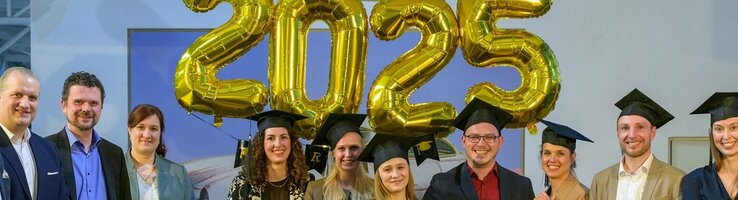 Abschlussevent Grow with ATLANTIC Eine Gruppe von Menschen in formeller Kleidung steht lächelnd unter goldenen "2025"-Ballons.