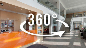 Virtuelle Tour ATLANTIC Hotel Kiel Heller Hotellobby-Bereich mit orangefarbener Rezeption und Treppe, 360-Grad-Ansicht.