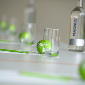 Tisch-Set-Up bei den ATLANTIC Hotels Konferenztisch mit grünen Bällen, Gläsern, Stiften und einer Wasserflasche, stilvoll arrangiert.