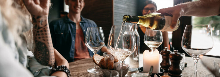 ATLANTIC Hotel Münster Essen & Trinken Gemütliche Runde im ATLANTIC Hotel Münster: Wein wird eingeschenkt, Kerzenlicht, Brot und Vorspeisen auf dem Tisch.