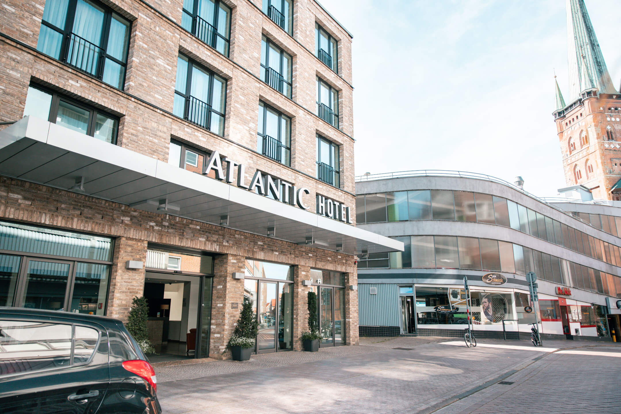 ATLANTIC Hotel Lübeck Hoteleingang Aussenansicht ATLANTIC Hotel Lübeck hotel entrance exterior view with church in the background