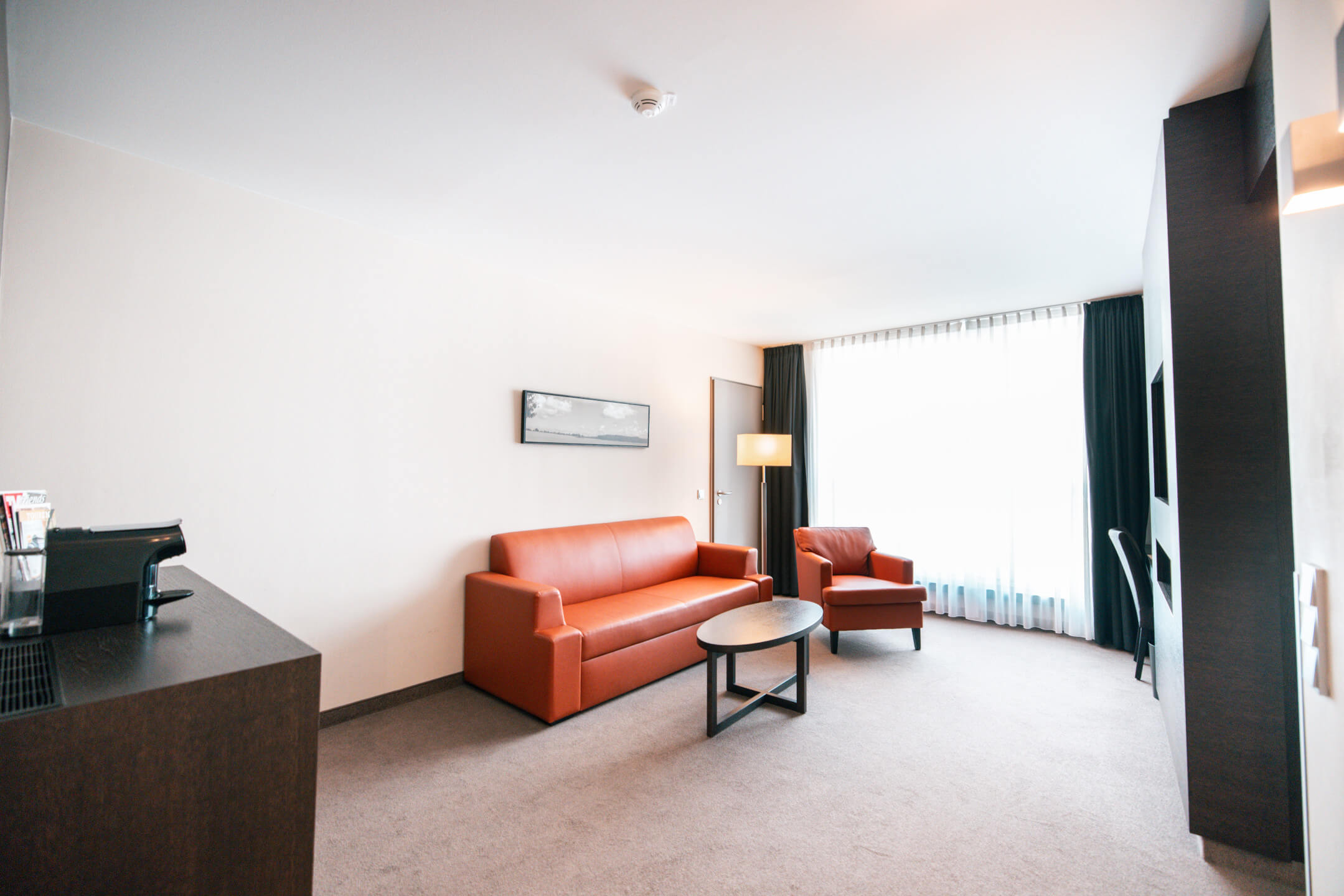 Wohnraum der Suite im ATLANTIC Hotel Lübeck Living room of the suite in the ATLANTIC Hotel Lübeck with couch and armchair