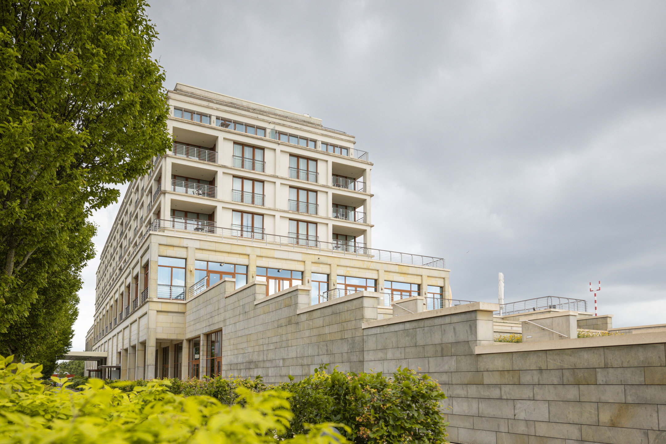 Die Außenansicht der Restaurantterrasse mit viel Grün vor bewölktem Himmel
