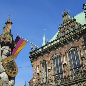 The Roland on the market place of Bremen  Statue of Bremen Roland and town hall facade with German flag, blue sky in the background.