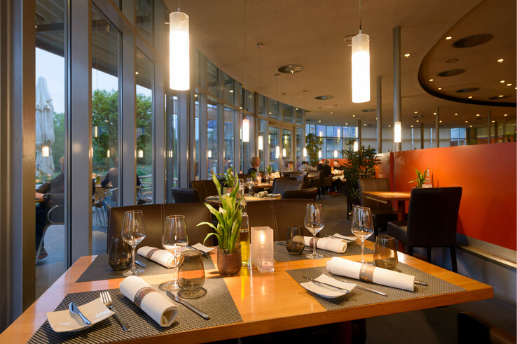 Restaurant CAMPUS in the ATLANTIC Hotel Universum Bremen Modern hotel restaurant with elegantly laid tables, large windows and atmospheric lighting in the ATLANTIC Hotel Universum.