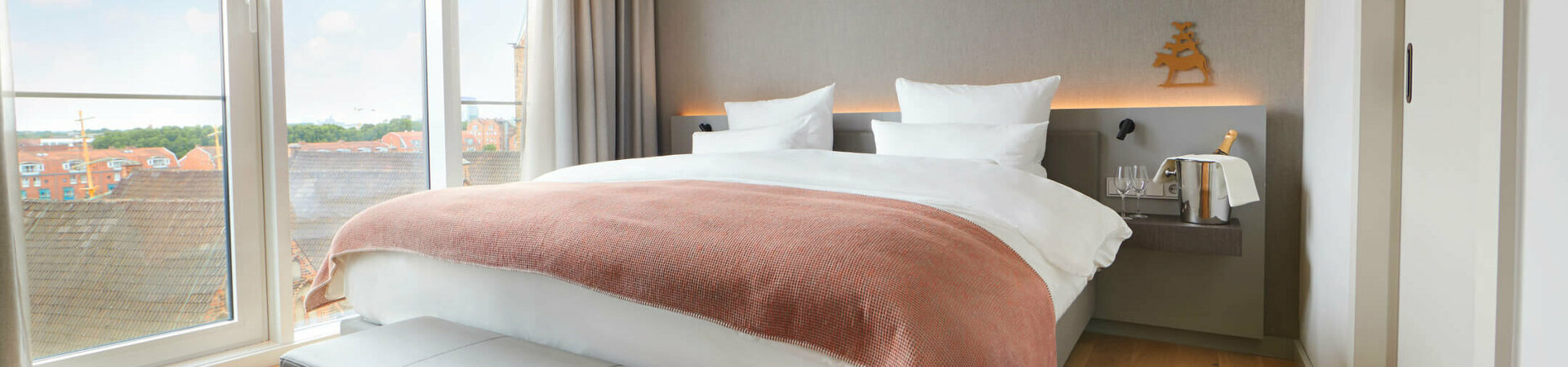 Balcony Suite sleeping area at the Atlantic Grand Hotel Bremen Bright hotel room with large bed, floor-to-ceiling windows and city view at the ATLANTIC Grand Hotel Bremen.