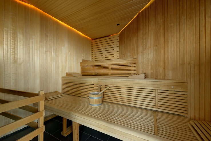 Wooden sauna with benches and a bucket in the ATLANTIC Hotel Sail City, Bremerhaven.