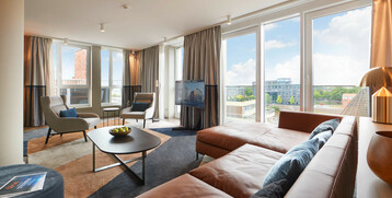 Grand Suite in the ATLANTIC Grand Hotel Bremen Bright hotel room with leather sofa, armchairs, large window and city view at the ATLANTIC Grand Hotel Bremen.