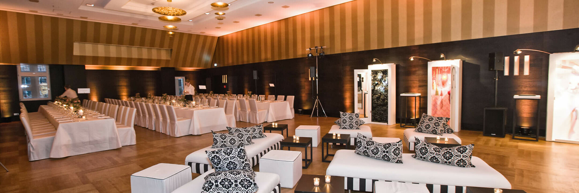 The Goldene Saal of the ATLANTIC Grand Hotel Bremen with lounge corner and long table Elegant event room in the ATLANTIC Grand Hotel Bremen with stylish seating and laid tables.
