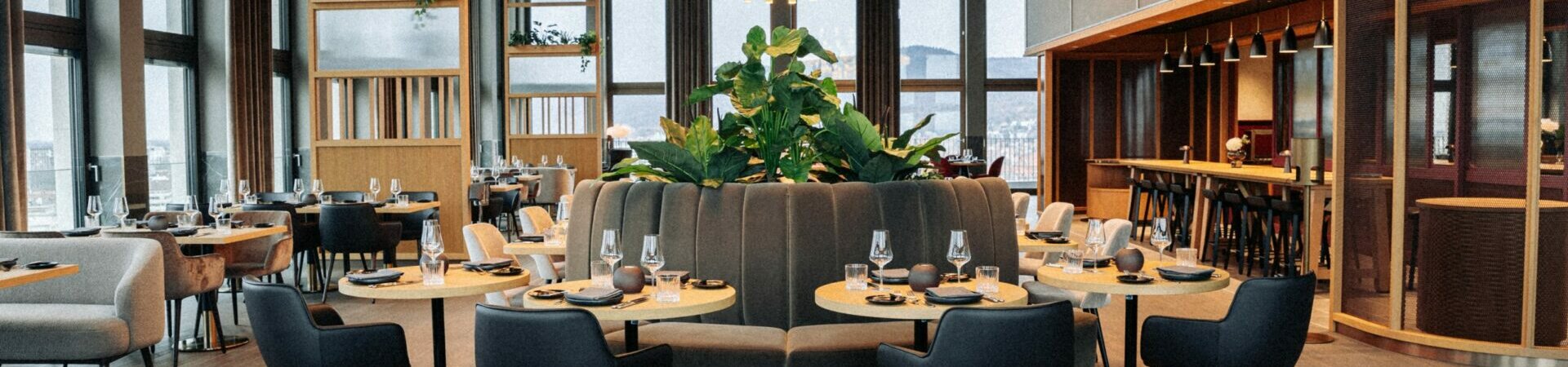 Restaurant 15 High on the 15th floor of the ATLANTIC Hotel Heidelberg Modern hotel restaurant with elegant tables, black chairs, large windows and stylish chandeliers.