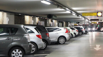 Bright underground parking garage with parked cars and signposts to the Rathaus/Münsterplatz exit at the ATLANTIC Grand Hotel Bremen.