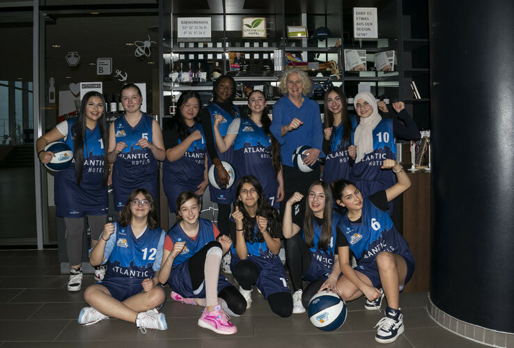 Team picture of the Eisbären Bremerhaven U14 girls team Youth basketball team poses in blue jerseys with basketballs at the ATLANTIC Hotel Sail City, Bremerhaven.