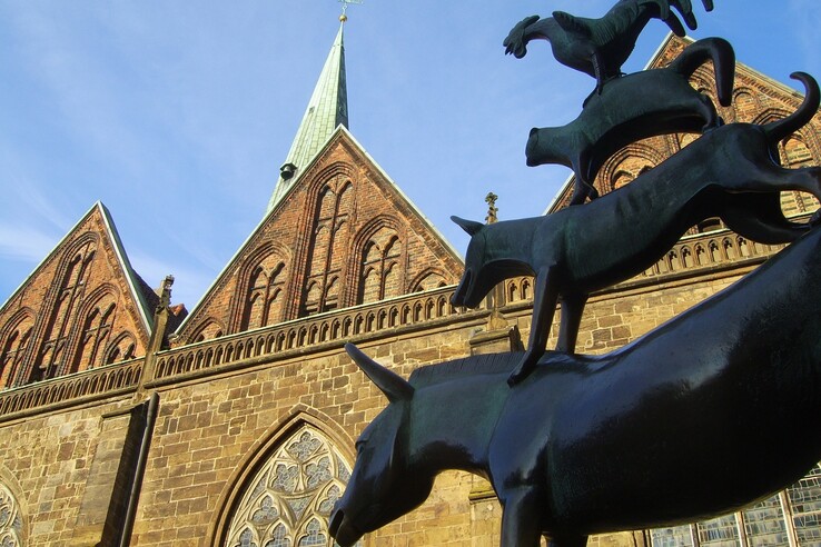 Statue of the Town Musicians of Bremen on the Bremen Market place Statue of the Bremen Town Musicians in front of a historic church in Bremen under a blue sky.