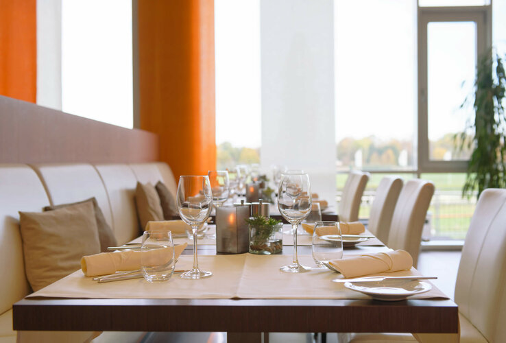 Restaurant Gottlieb im ATLANTIC Hotel Galopprennbahn Modernes Restaurant mit elegant gedeckten Tischen, weißen Stühlen und großen Fenstern im ATLANTIC Hotel Galopprennbahn.