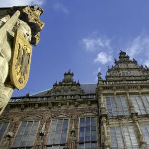 Roland statue and Bremen town hall Historic building in Bremen with ornate stone relief and blue sky in the background.