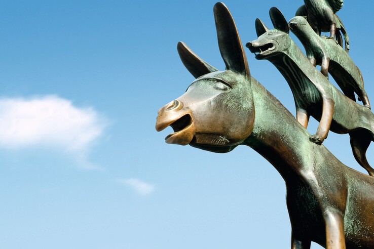 Statue of the Town Musicians of Bremen on the market place in Bremen Bronze statue of the Bremen Town Musicians against a blue sky, showing a donkey, dog, cat and cockerel.