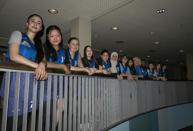 Co-operation Eisbären Bremerhaven U14 with ATLANTIC Hotel Sail City A group of young women in blue jerseys lean against a railing in the ATLANTIC Hotel Sail City.