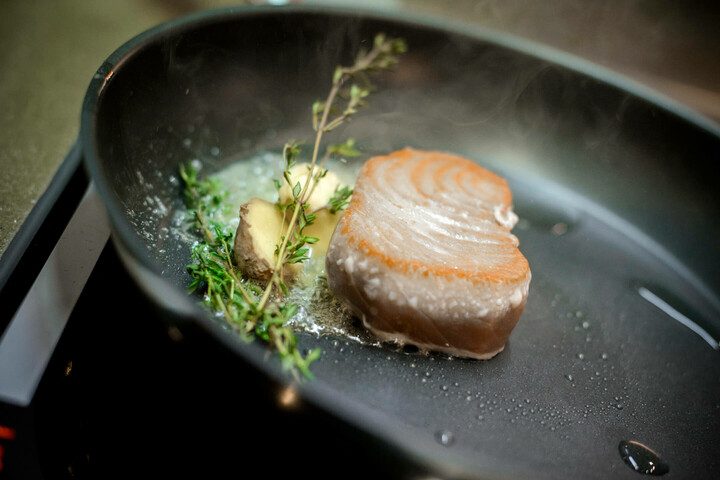 Food and beverage for your event in Lübeck A tuna steak with thyme and ginger fried in a pan.