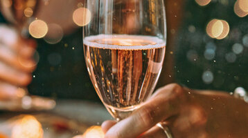 Two people are holding champagne glasses in a festive setting.