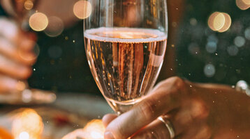 Two people are holding champagne glasses in a festive setting.