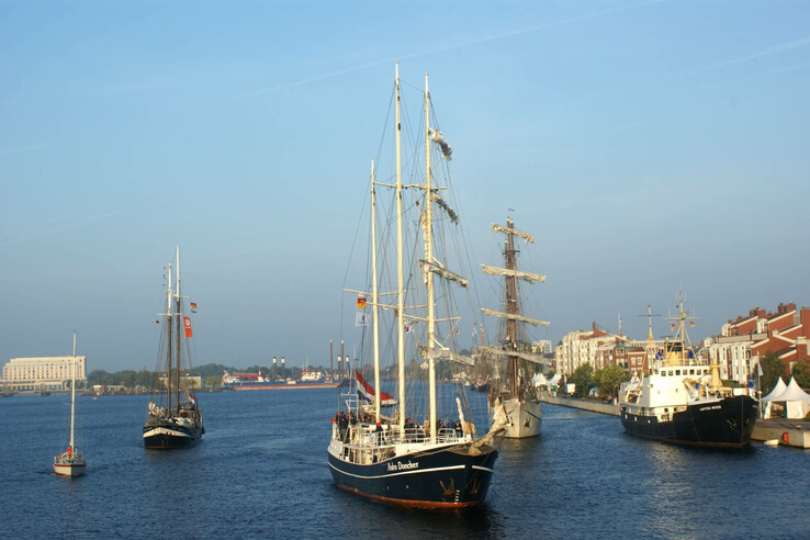 Wilhelmshaven CUP Sailing ships in the harbor against a city backdrop under a clear sky.