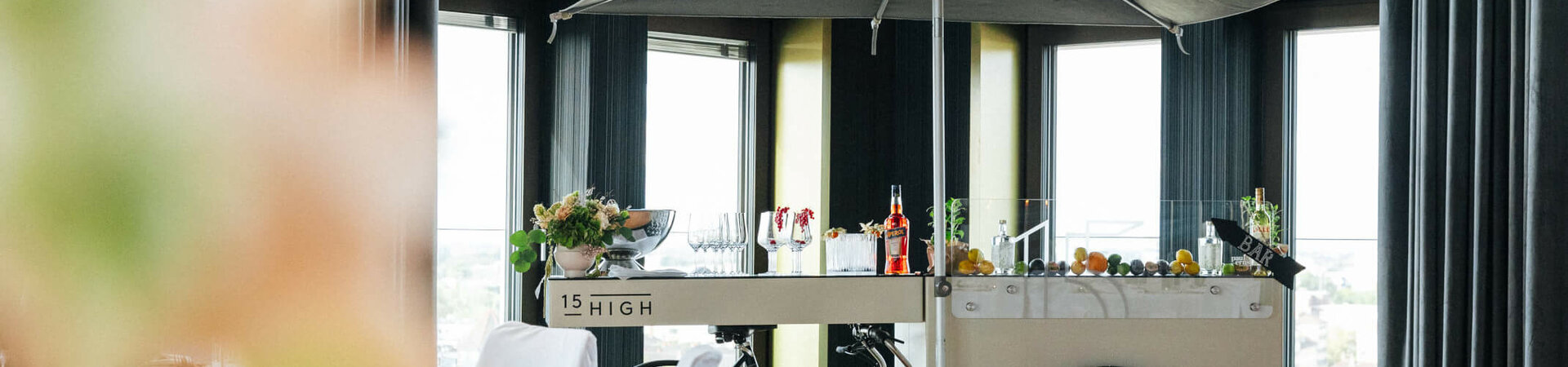 Mobile bar trolley with parasol in an elegant hotel room, decorated with flowers and drinks.