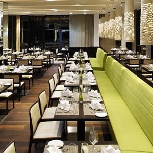 Ein Restaurant mit mehreren Tischen, einer Langen Bank in einem hellen modernen Raum.