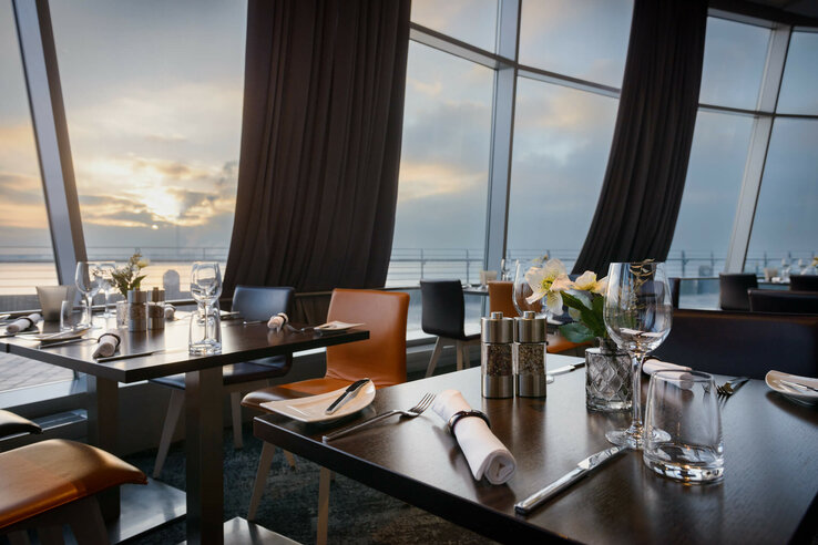 Restaurant Strom in the ATLANTIC Hotel Sail City Modern restaurant with set tables and sea view at sunset in the ATLANTIC Hotel Sail City, Bremerhaven.