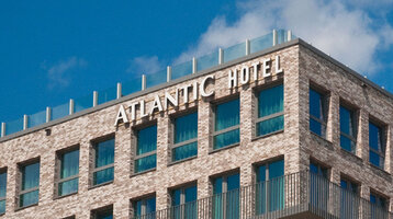 Außenansicht des ATLANTIC Hotel Kiel Fassade des ATLANTIC Hotel Kiel aus Backstein mit großen Fenstern und dem Hotelnamen in weißen Buchstaben.