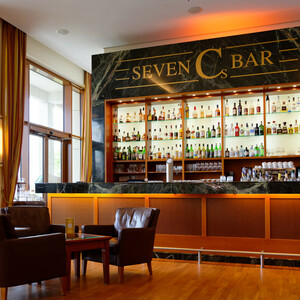 Seven Cs Bar in the ATLANTIC Hotel Wilhelmshaven Elegant hotel bar with illuminated shelves full of spirits, comfortable leather armchairs and wooden floor.