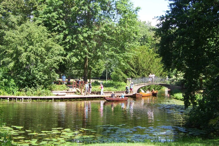 Rowers on the lake in the Bürgerpark Bremen Green park landscape with a pond, boats and a bridge near the ATLANTIC Hotel Universum, Bremen.
