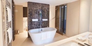 Bathtub of the Grand Suite at the Atlantic Grand Hotel Bremen Modern bathroom with free-standing bathtub, towel rail, double washbasin and elegant marble wall in the ATLANTIC Grand Hotel Bremen.