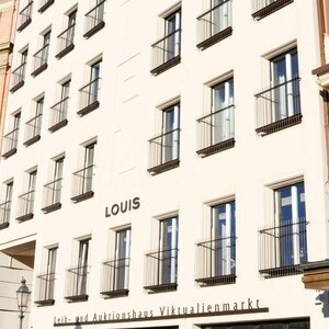 LOUIS Hotel in München Fassade des LOUIS Hotels in München mit mehreren Fenstern und einem historischen Nachbargebäude.