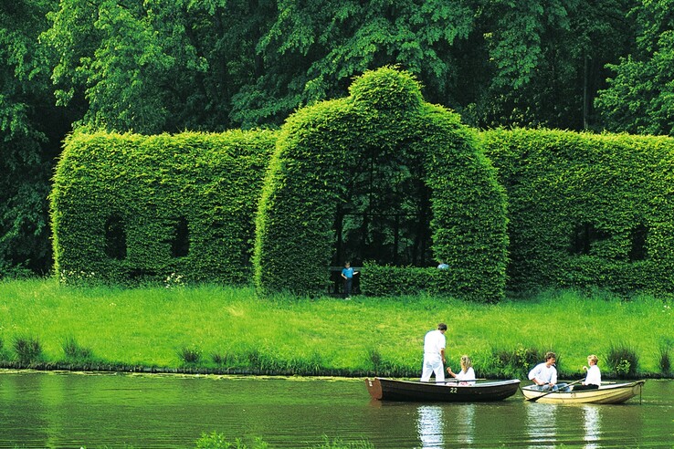 Rowers on the lake in the Bürgerpark Bremen People rowing on a pond in front of an ornate green hedge in Bürgerpark near the ATLANTIC Hotel Universum in Bremen.